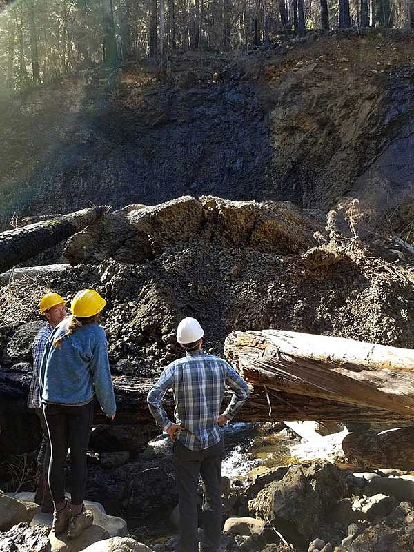 Researchers looking up at a hillside from a rocky river bed