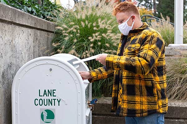 A student putting their ballot into the drop box