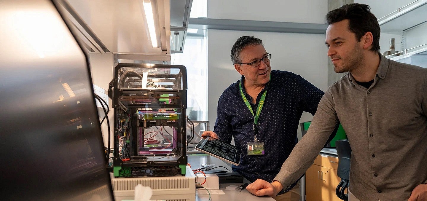 Two male UO researchers in a lab discussing research