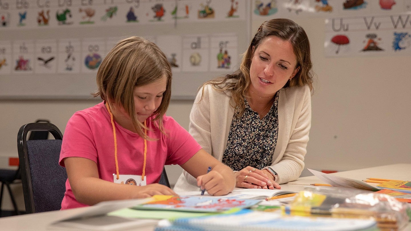 a graduate student engages in a classroom activity with a student