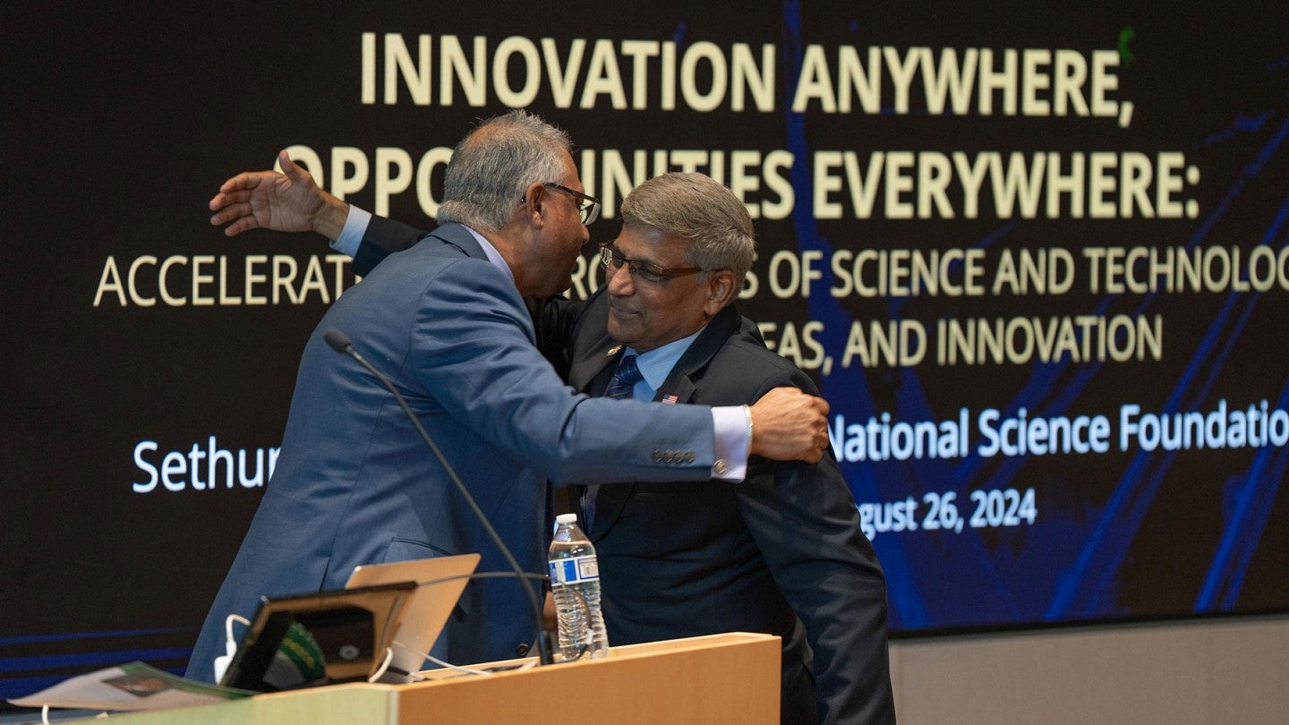 NSF Director Sethuraman Panchanathan greets a colleague on stage during a visit to the UO in Eugene