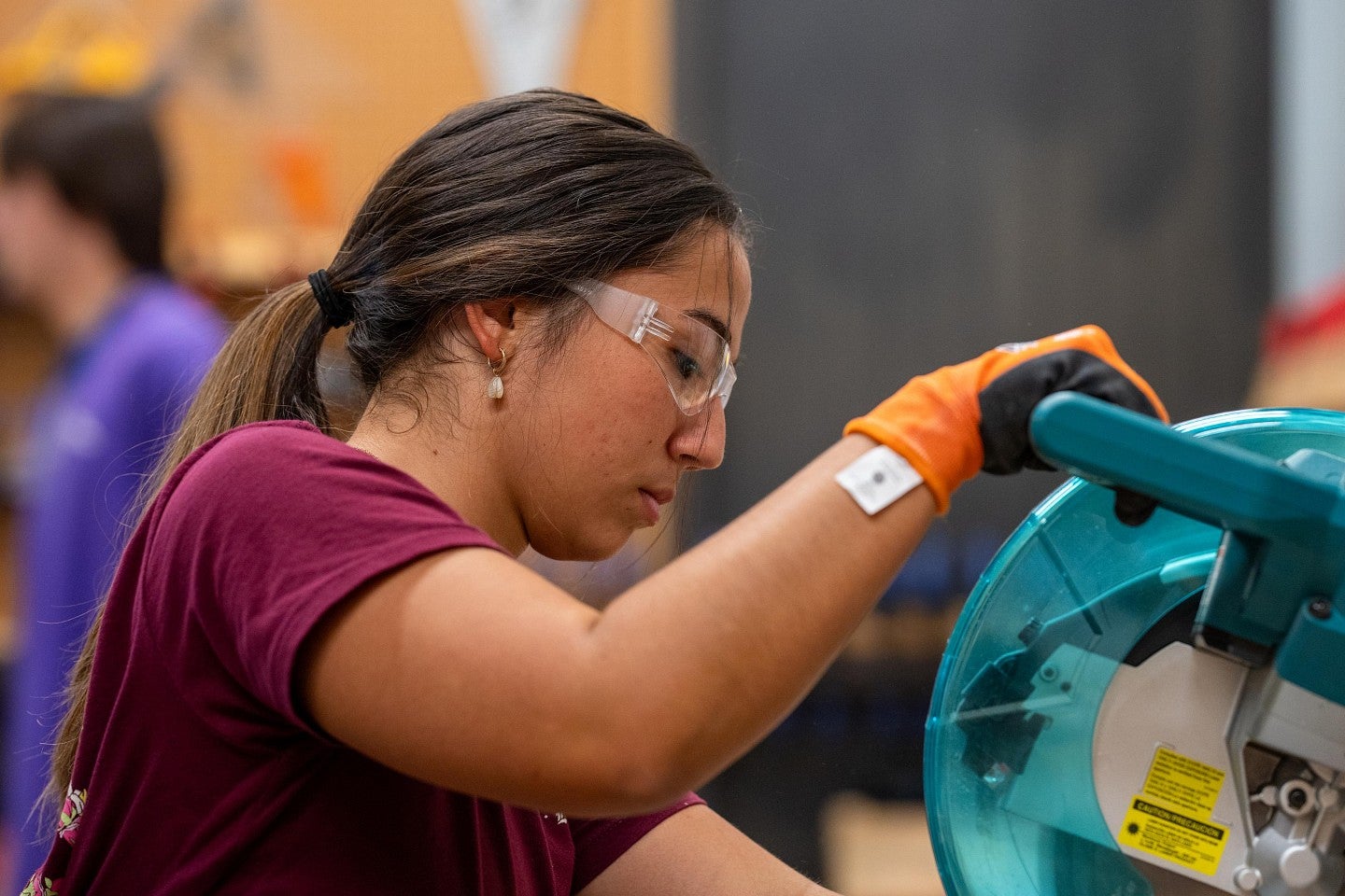 A student in a woodshop using a chopsaw during the Bruton Design Intensive