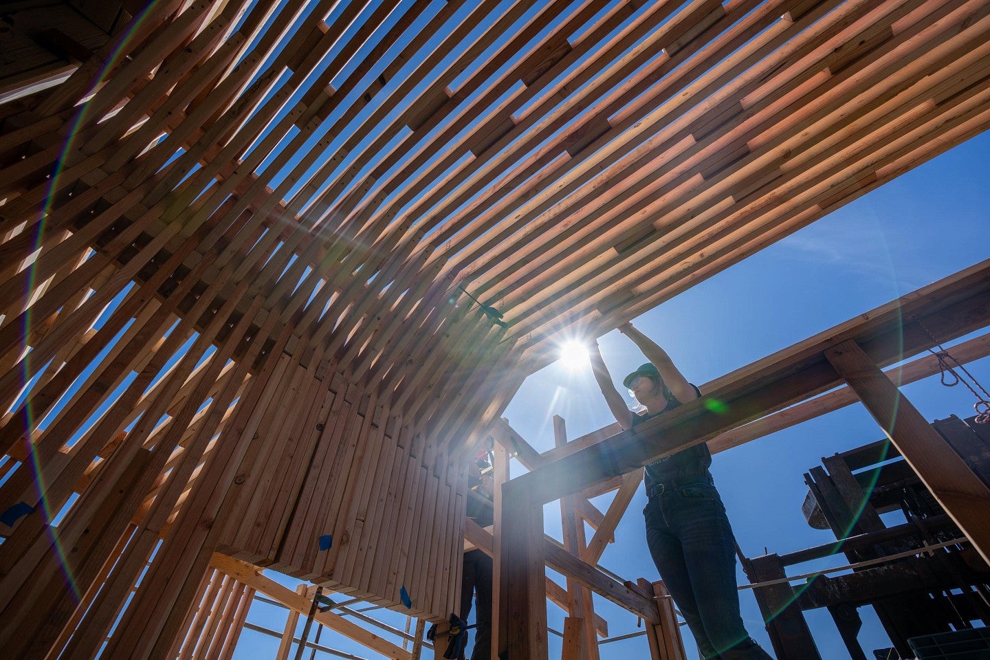 A student installing a section of the new home's roof supports during the Bruton Design Intensive