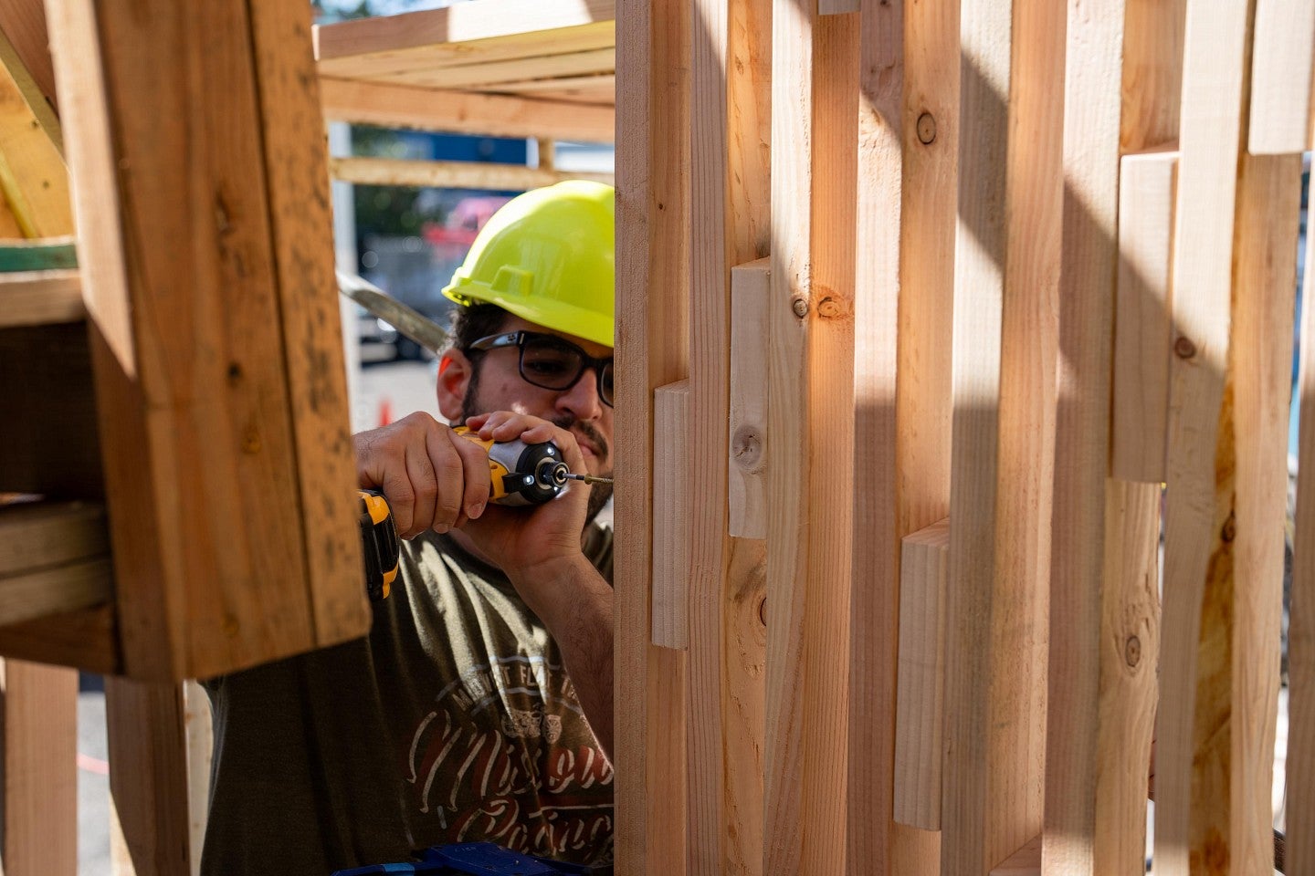 A student using a power drill during construction of a home during the Bruton Design Intensive