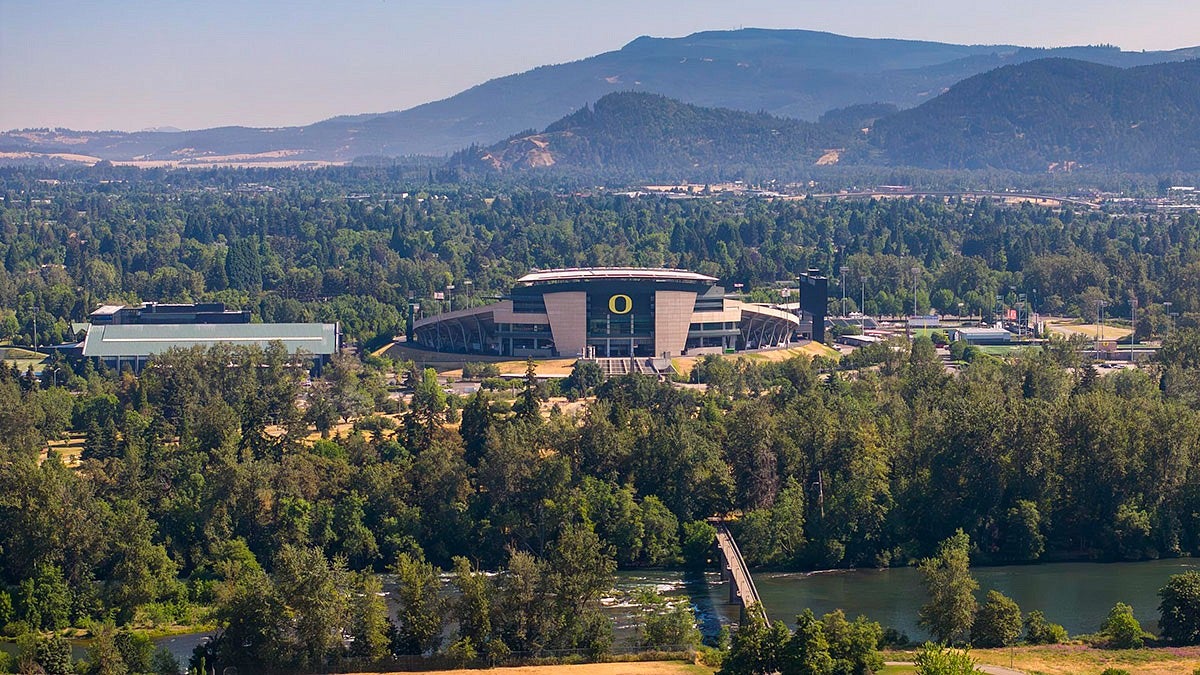 aerial view of Autzen Stadium with the Willamette River in the foreground and Cascade foothills in the background