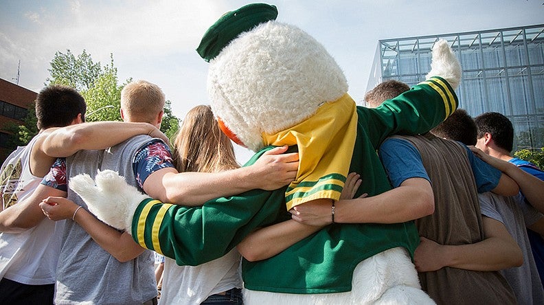 A view of the back of the Duck arm in arm with six students, three on each side