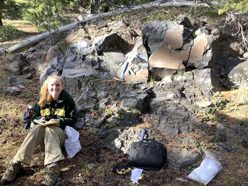 Annika Dechert takes notes while sitting near a rocky rhyolite outcrop on the South Sister mountain.