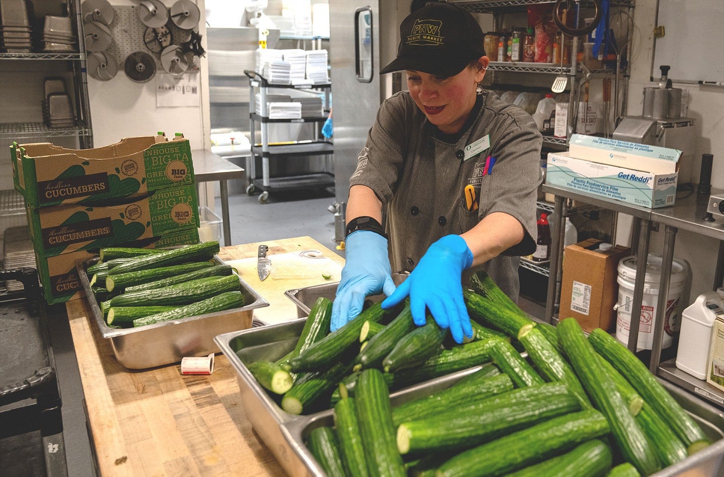 A dining services worker prepares piles of cucumbers