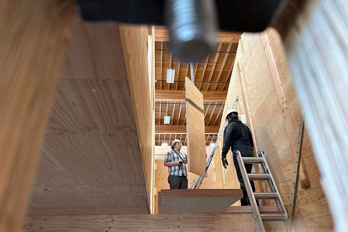 two people work on the interior of a mass plywood prototype house