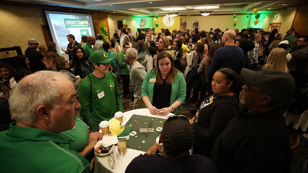 Two teenagers and their parents chatting around a table at a recruitment event