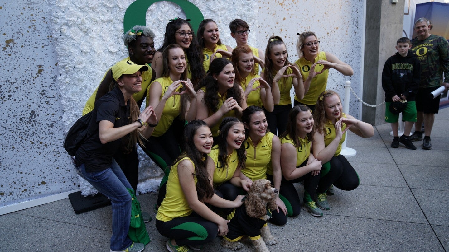 Oregon fan and dog along with Oregon cheerleaders holding their O with their hands