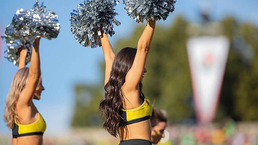 Two UO cheerleaders with their arms up