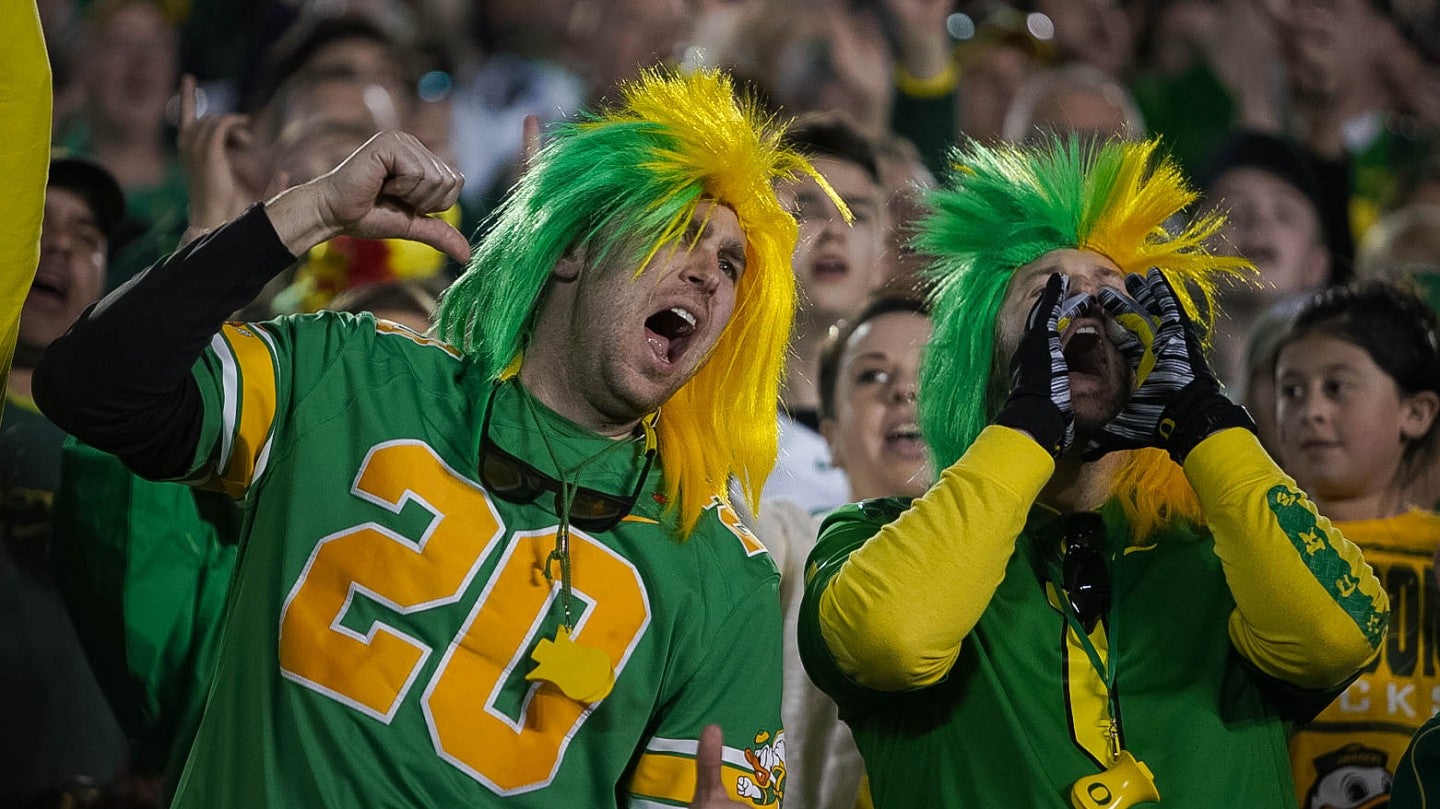 Two male UO fans cheering on the football team at a game