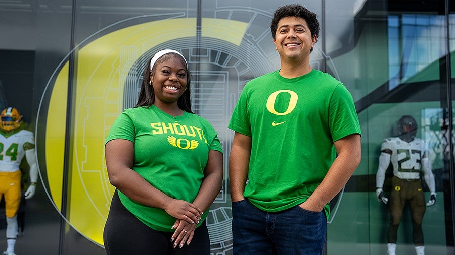 A female and male student smiling for the camera wearing Duck tshirts