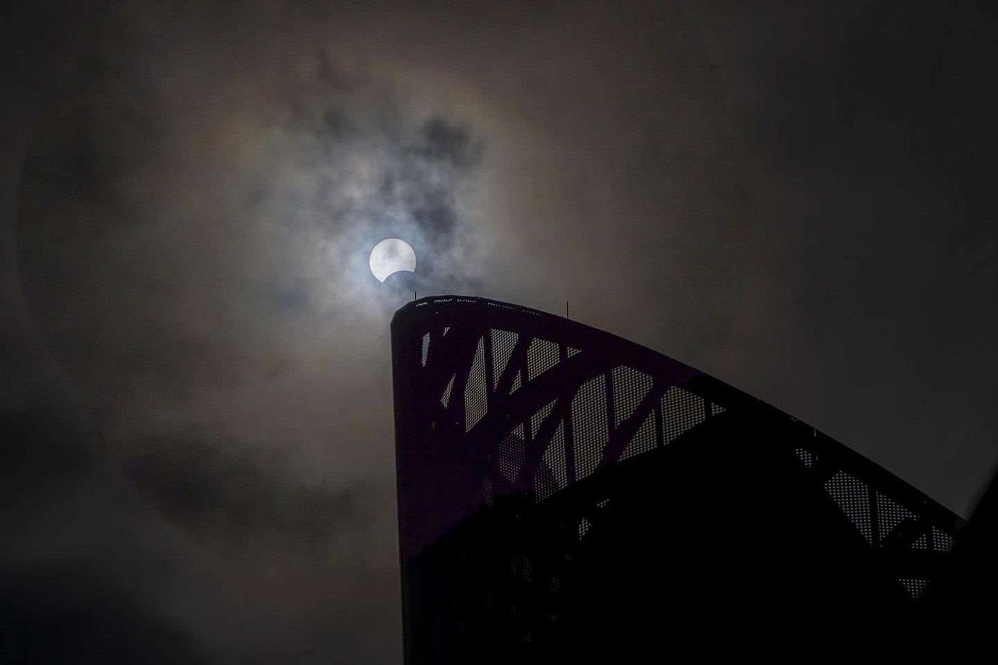 a partial eclipse visible over Hayward Field through the clouds 