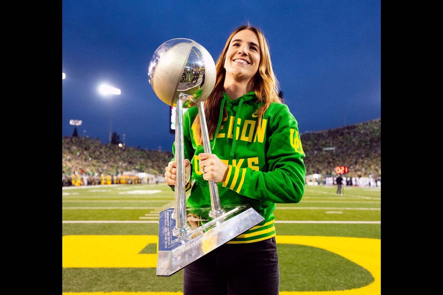 Sabrina Ionescu holding the WNBA Championship trophy in front of stadium crowd