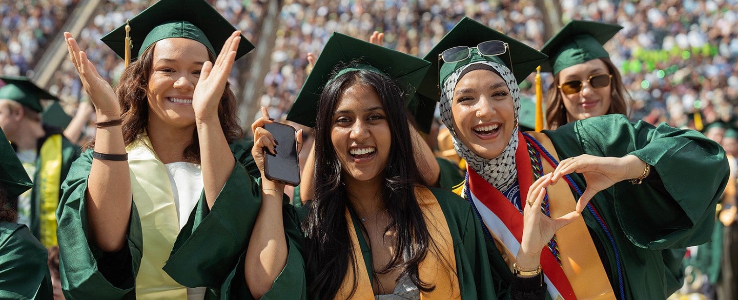 Three female graduates smiling during the UO commencement ceremony