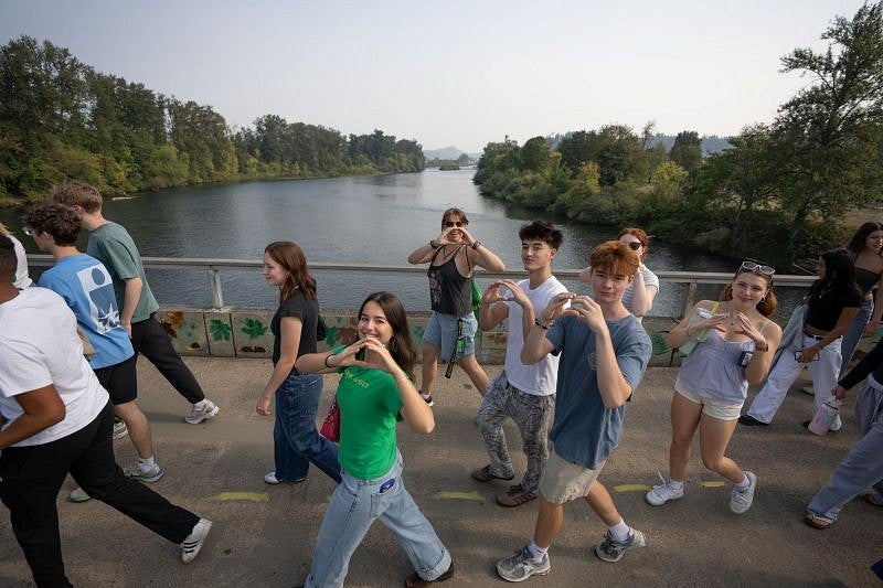 students making an O with their hands as they cross a bridge over the Willamette River
