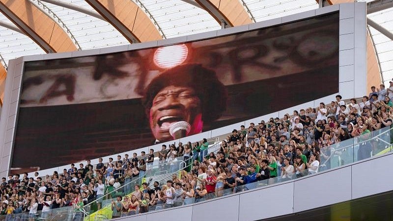 a video of the song Shout playing on the large screen at Hayward Field with people in the stands below