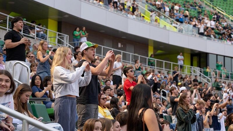 students standing and cheering in the stands of Hayward Field during convocation