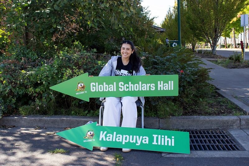 student holing signs in the shape of arrows directing people to resident halls
