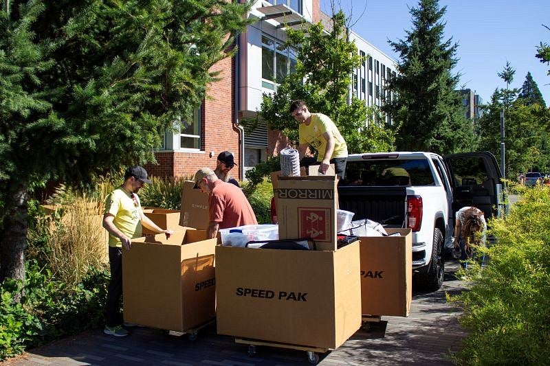 Volunteers help a student and family member unload belongings from a truck into boxes
