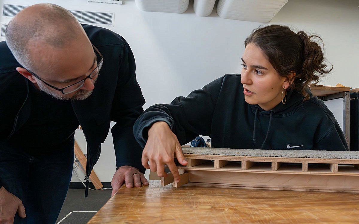 a student shows a model of a building design