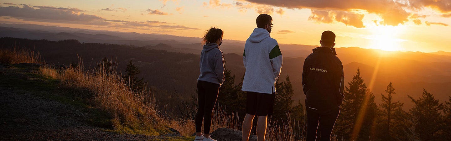 three students watch a sunset from the top of Spencer Butte in Eugene