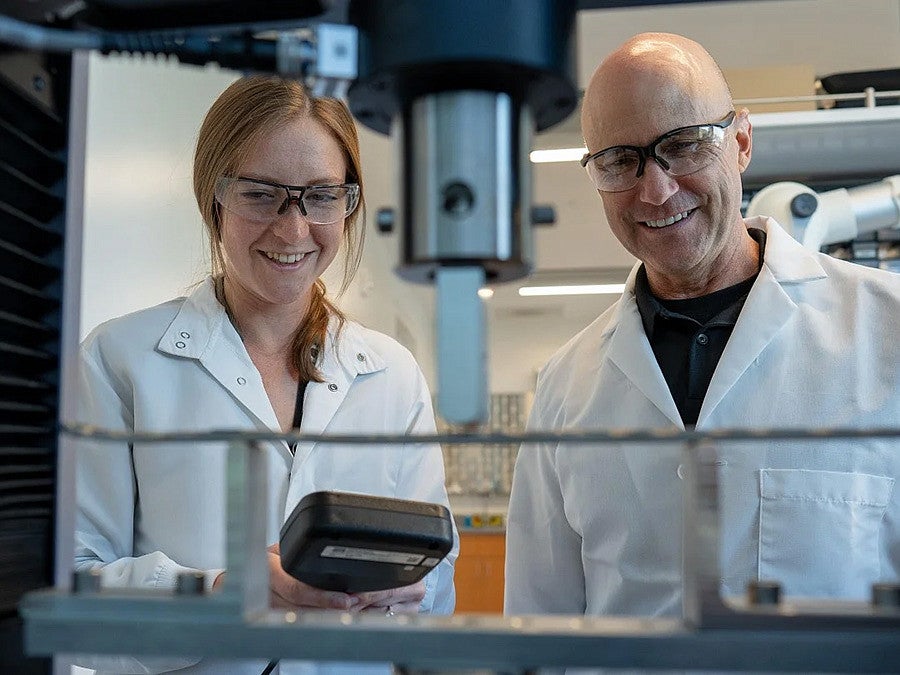 Kylie Williams and Bob Guldberg working with equipment in the lab