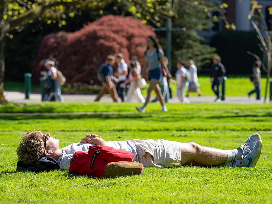 a student appears to nap in the grass on campus
