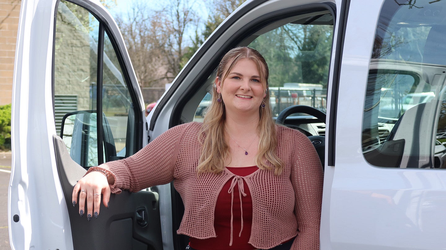 A woman stands in the crook of a door and the inside of a van