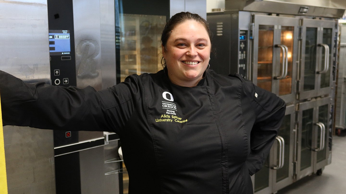 A woman leans against a wall in a catering kitchen