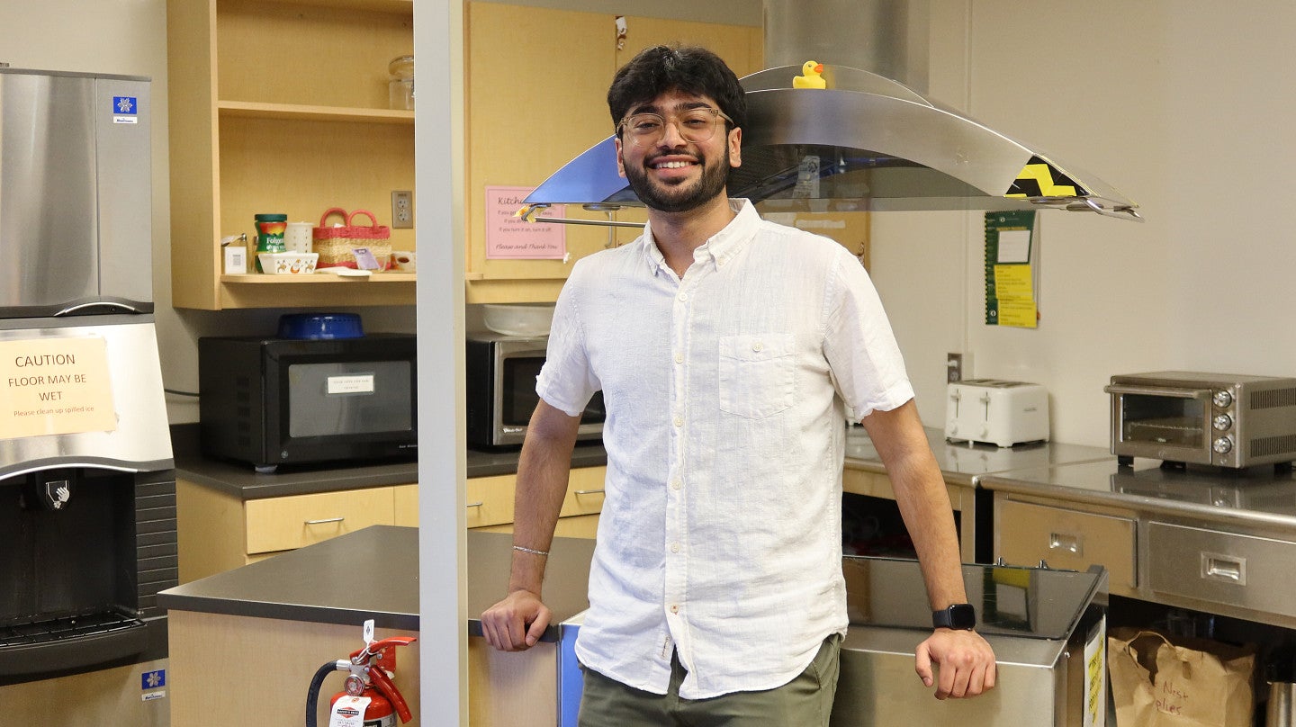 A man stands against a cooking island in a kitchen