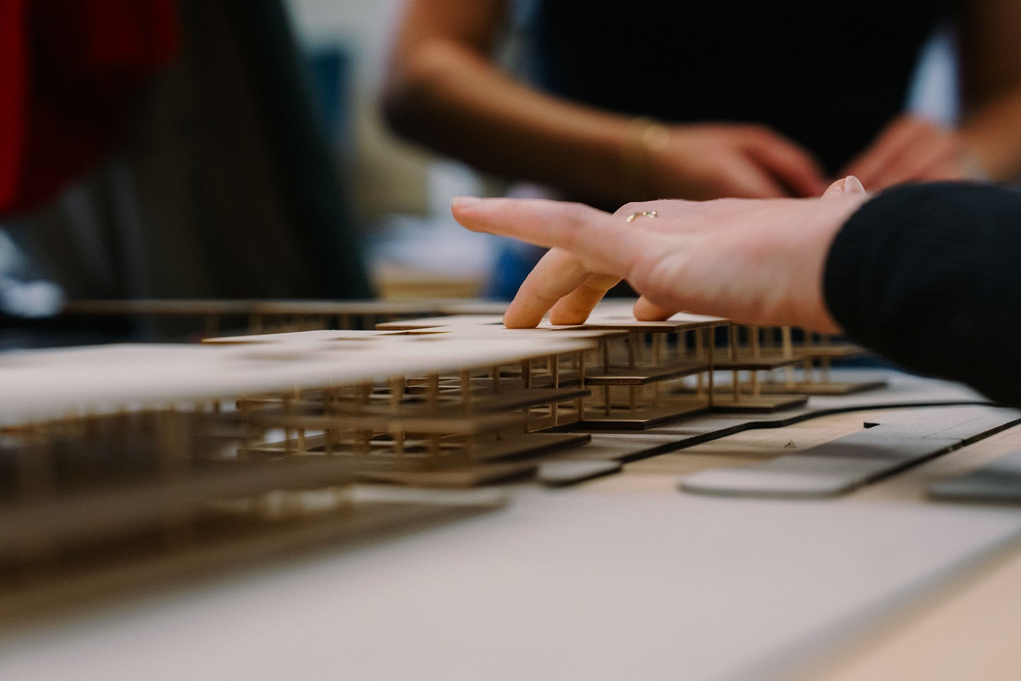 A student's hand touches a model-sized rendition of a design plan for an airport