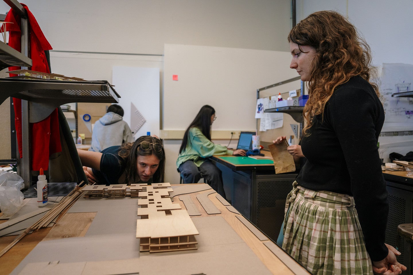 A student bends down to get a table-level perspective on a model of an airport
