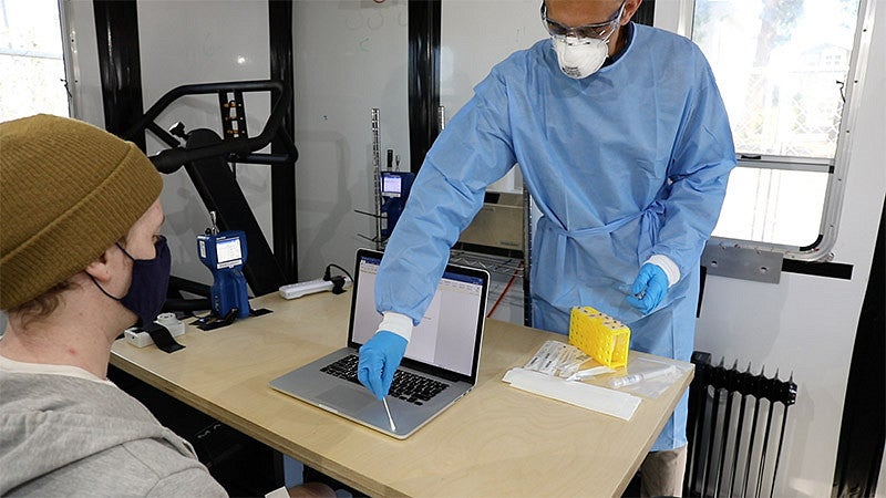 Doctoral student Hooman Parhizkar collects a sample from surfaces in a room used to study viral transmission