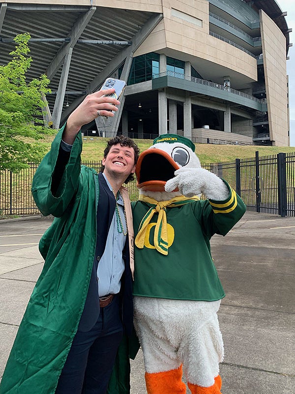 Student taking a selfie with the Duck at the 2022 UO graduation at Autzen Stadium