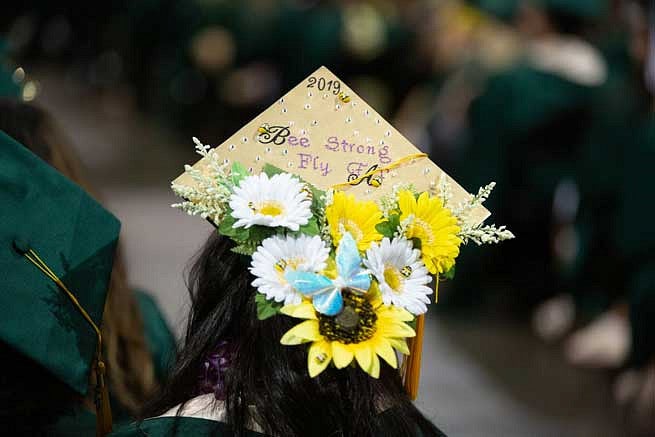 Mortar board that says Be Strong, Fly with flowers and bees on it Mortar board that says Be Strong, Fly with flowers and bees on it