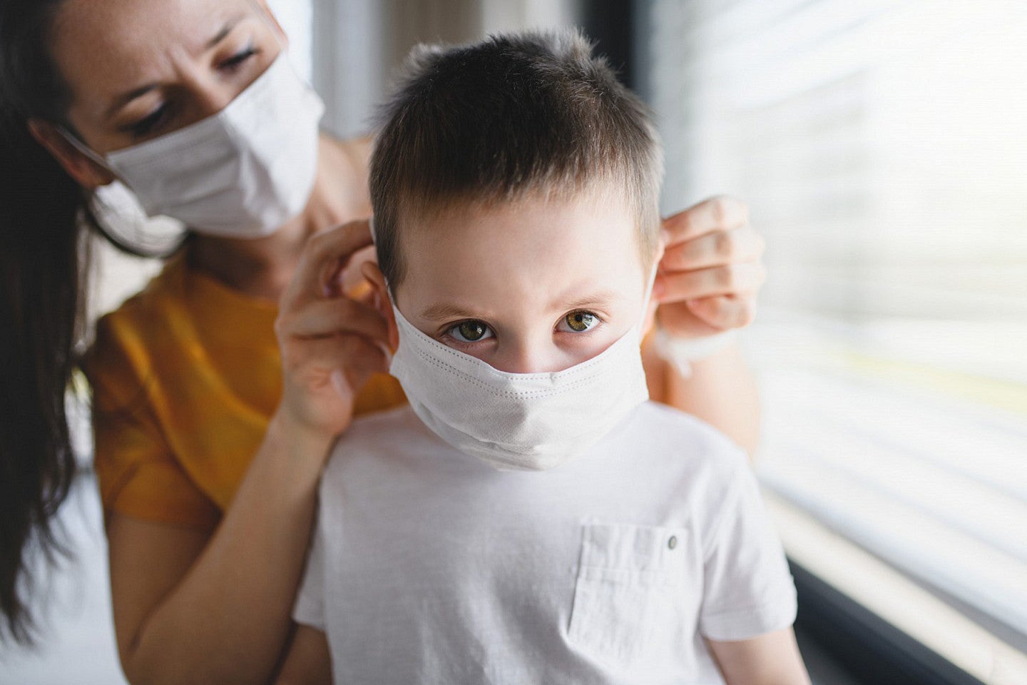 Woman helping young child to fit mask