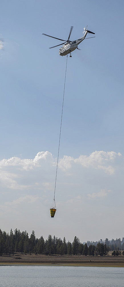 Firefighting helicopter with a bucket getting water from a lake