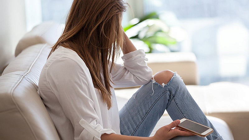 Woman with a phone sitting on a couch