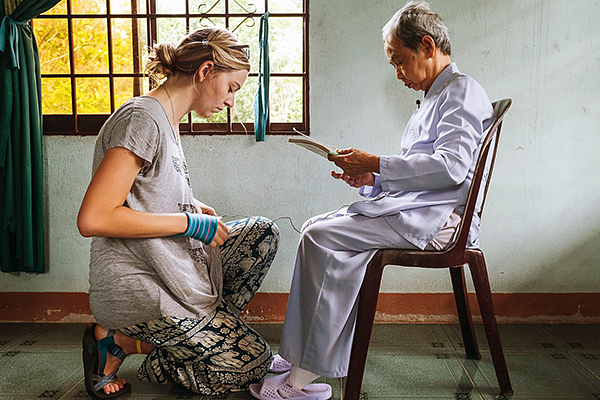 a student connects microphone wires in preparation to interview a seated person