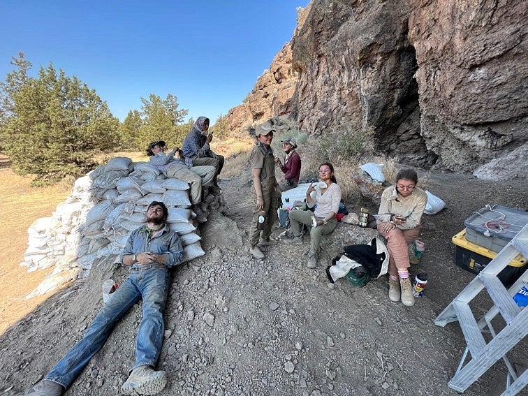 Several people are covered in dust. They eat lunch and one is laying down, stretched out with his eyes closed.