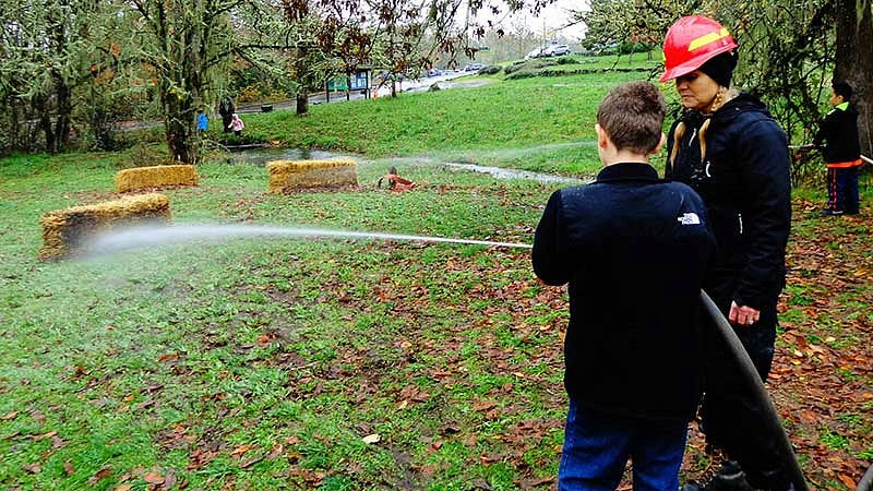 Firefighter showing a young man how to use the firehose