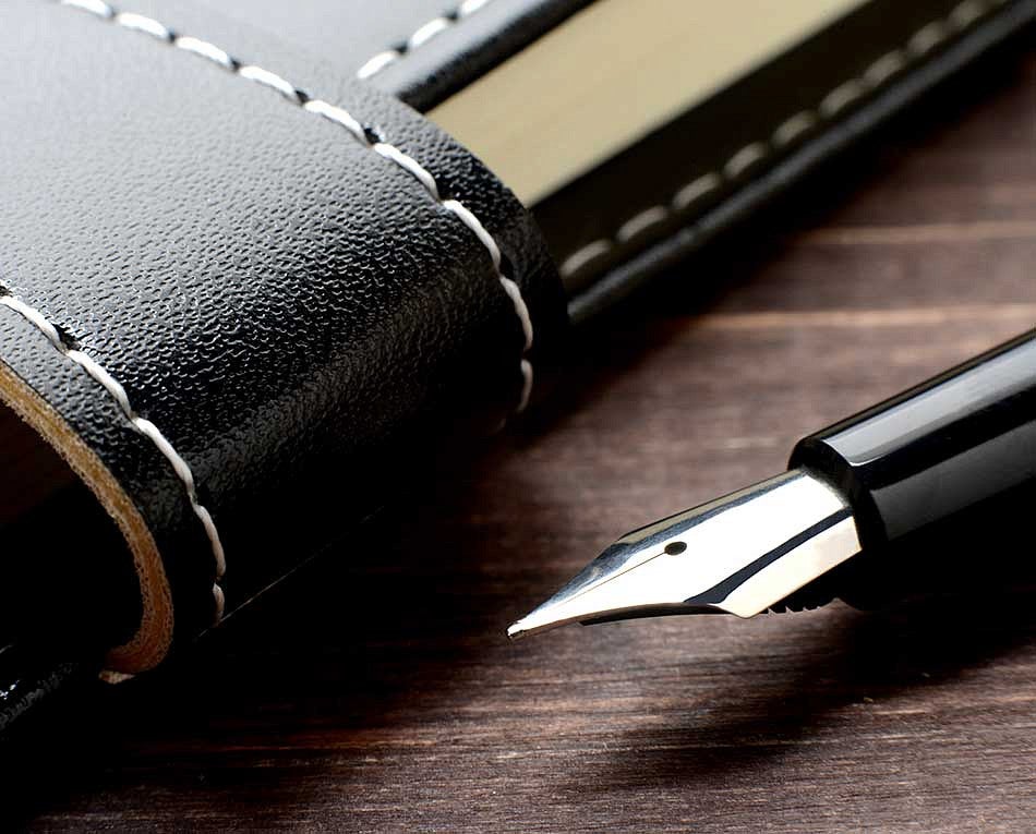 Black fountain pen next to a notebook