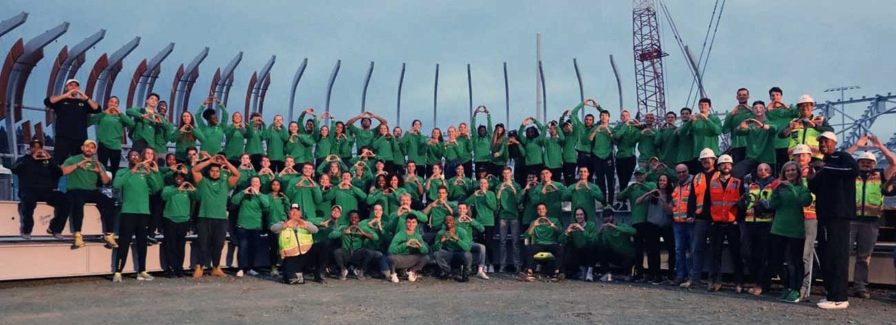 Members of the Oregon Track and Field team and construction workers throwing the O at Hayward Field