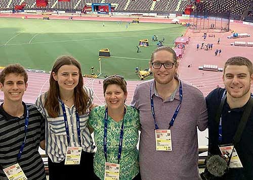 Group photo of SOJC students with a backdrop of the track in Doha