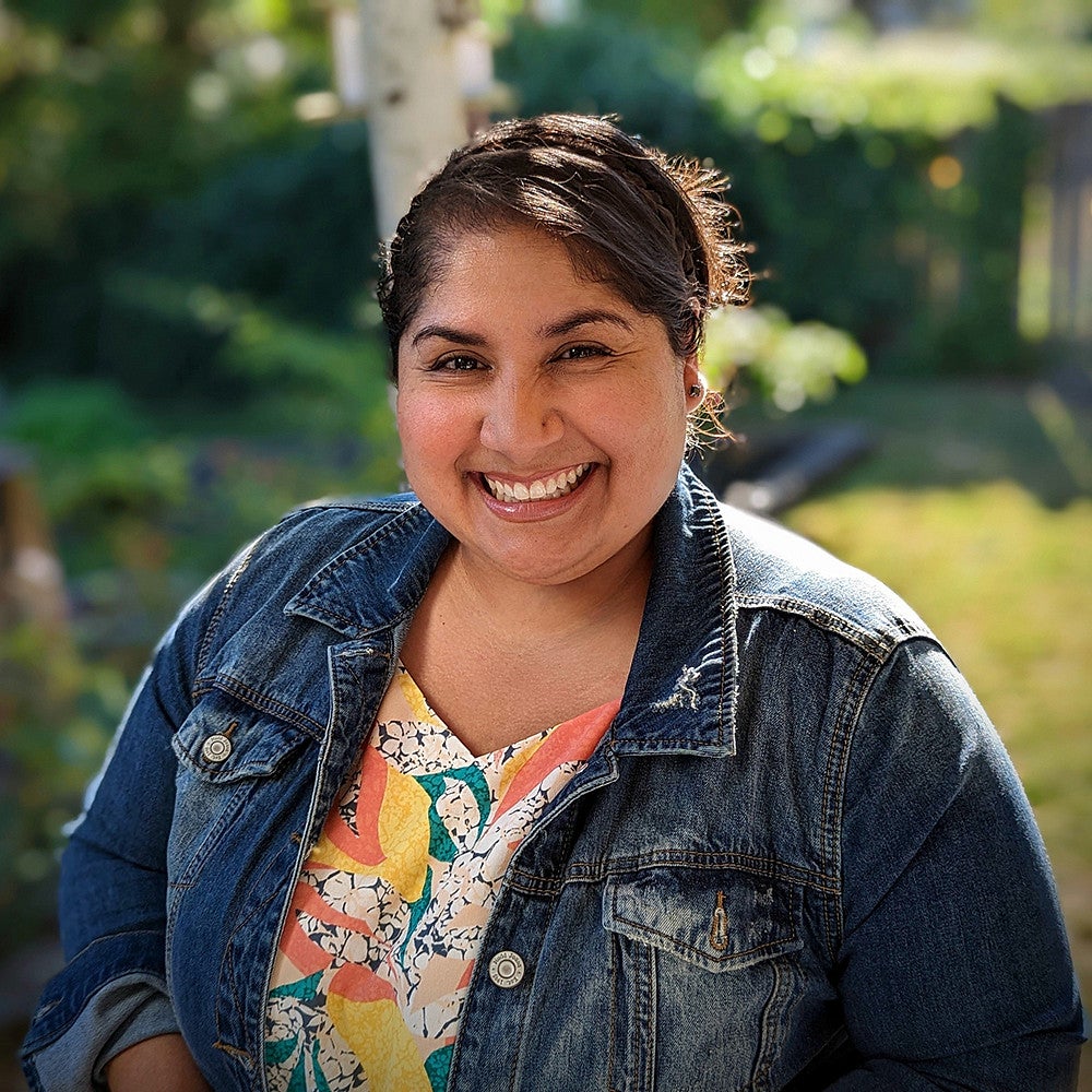 Woman with big smile, wearing a denim jacket.