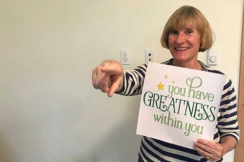 A professor holding a sign that says You have greatness within you