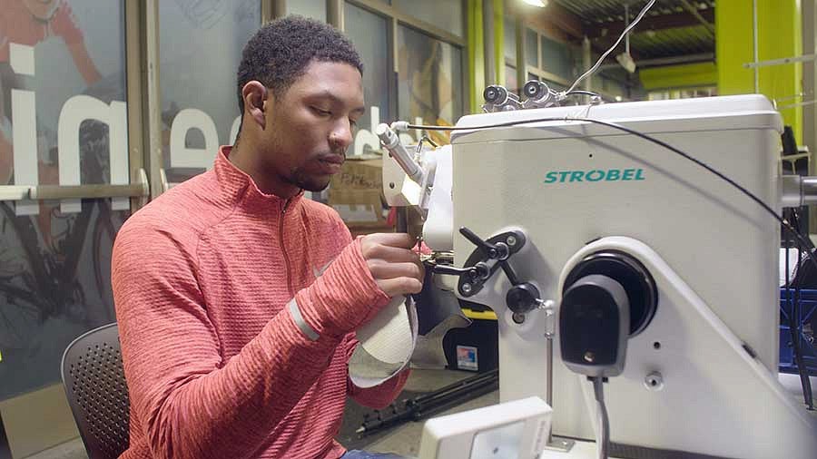 Kodi Whitfield sewing the soles of athletic shoes